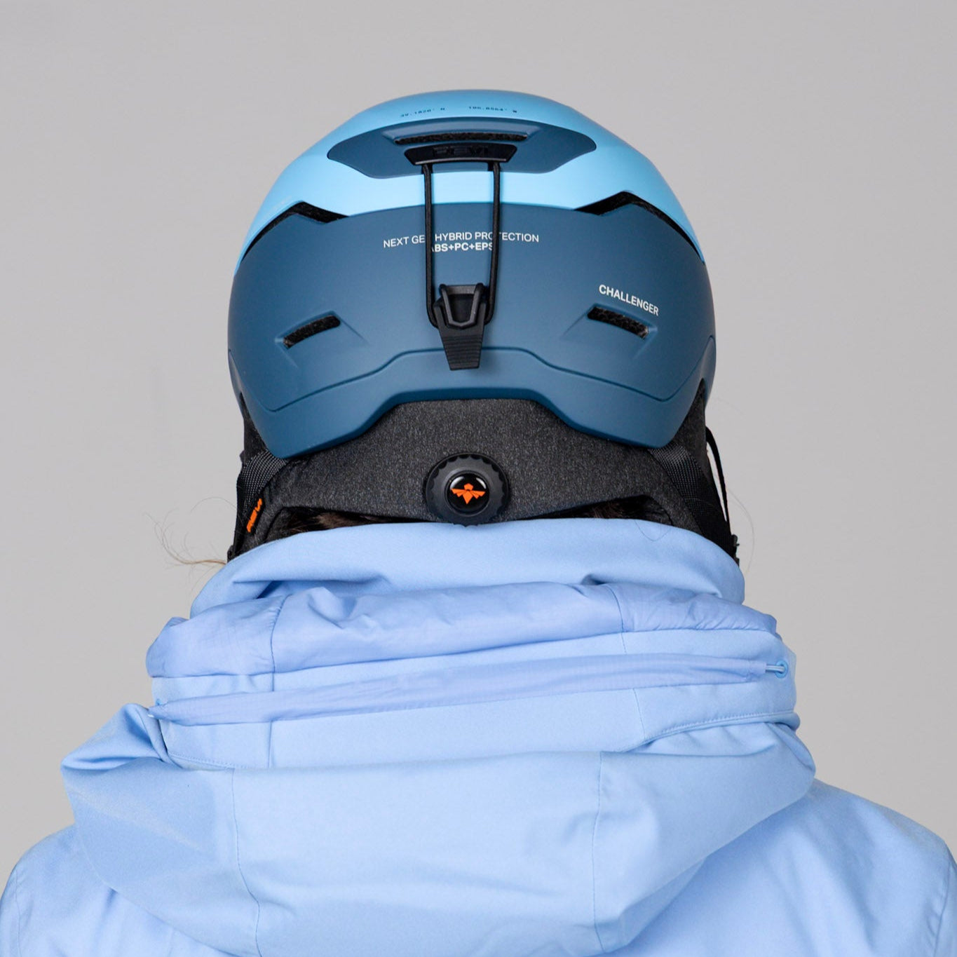 Person wearing a blue helmet and light blue jacket against a gray background